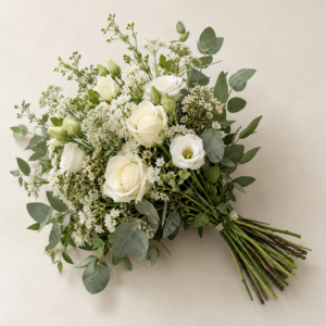 White roses and lisianthus with fresh green foliage in a hand-tied bouquet